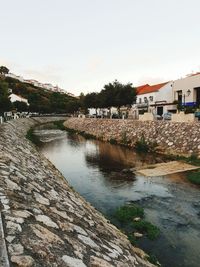 Scenic view of river by buildings against sky