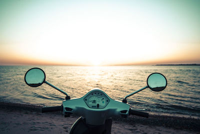 Deck chairs on beach against clear sky during sunset