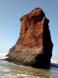 Rock formation on beach against clear sky