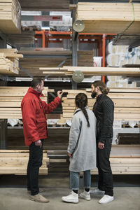 Salesman assisting couple in buying wooden planks in hardware store