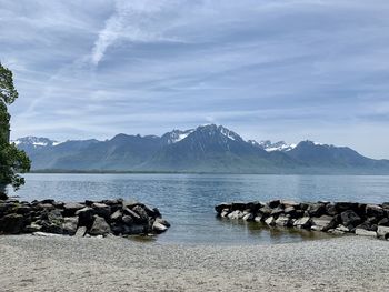 Scenic view of sea by mountains against sky