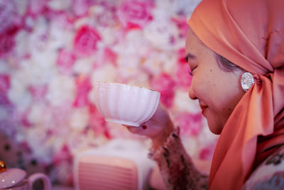 Close-up of woman holding glass of red rose