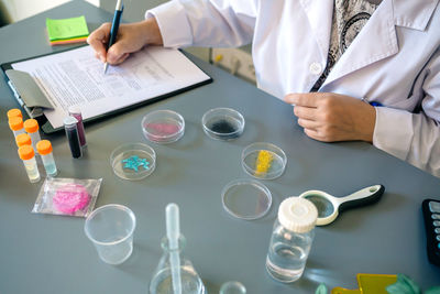 Unrecognizable female scientist examining glitter samples in petri dishes on laboratory