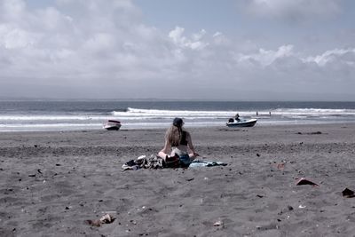 Rear view of people on beach against sky