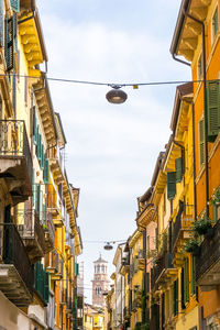 Low angle view of lamp hanging amidst buildings in city