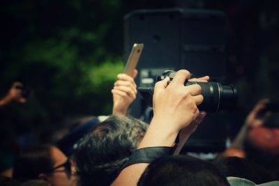 Copped hand of person photographing amidst crowd