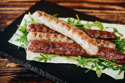 Close-up of roasted sausages with leaf vegetables on slate