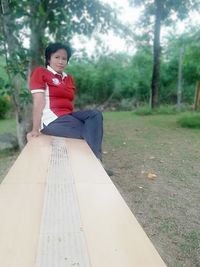 Portrait of young woman sitting on tree trunk