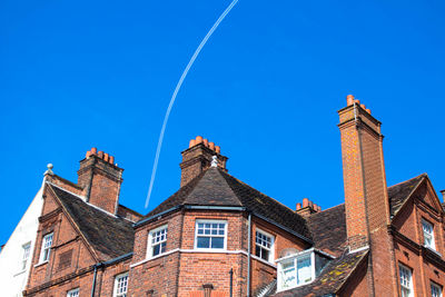 Low angle view of old building against vapor trail in clear blue sky