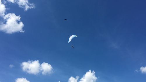 Low angle view of paragliding against blue sky