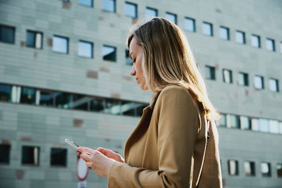 Caucasian woman using smartphine at city street