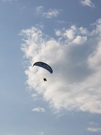 Low angle view of person paragliding against sky