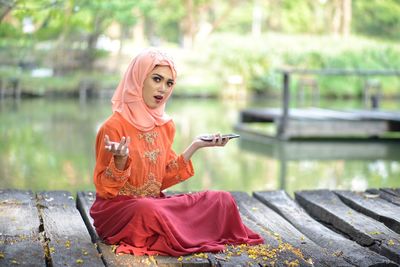 Young woman using mobile phone while sitting outdoors