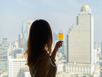 Rear view of woman looking at city buildings against sky