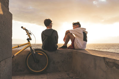 Rear view of men sitting on bicycle at beach