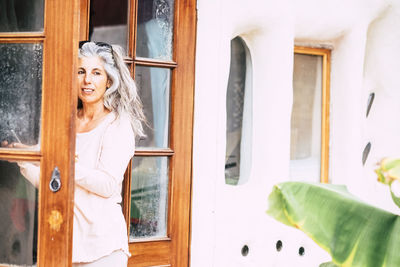 Mature woman standing by door of house