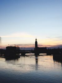 Silhouette bridge over river against sky during sunset