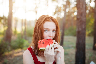 Portrait of young woman eating watermelon at park