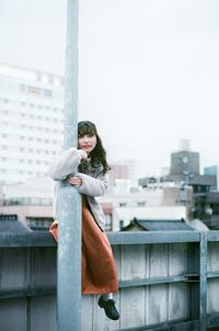 Portrait of woman standing against building in city