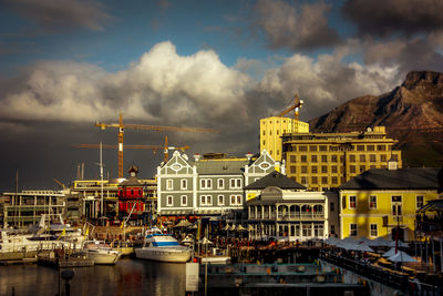 Boats in river by buildings in city against sky
