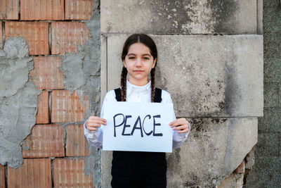 Portrait of girl holding poster against wall