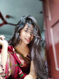 Low angle portrait of young woman wearing sari at home