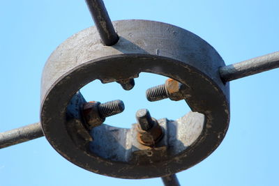 Low angle view of rusty wheel against clear blue sky