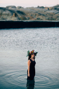 Young woman standing by lake against sky