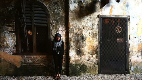 Woman standing against old house