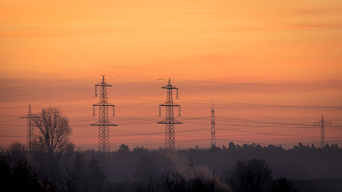 Silhouette electricity pylon against sky during sunset