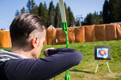 Man aiming bow while standing outdoor