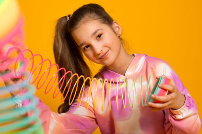 Portrait of young woman against yellow background