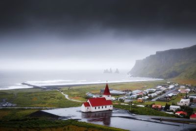 Buildings by sea against sky