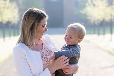 Side view of mother carrying daughter at park