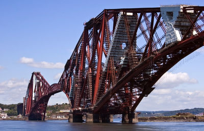 Bridge over river in city against sky