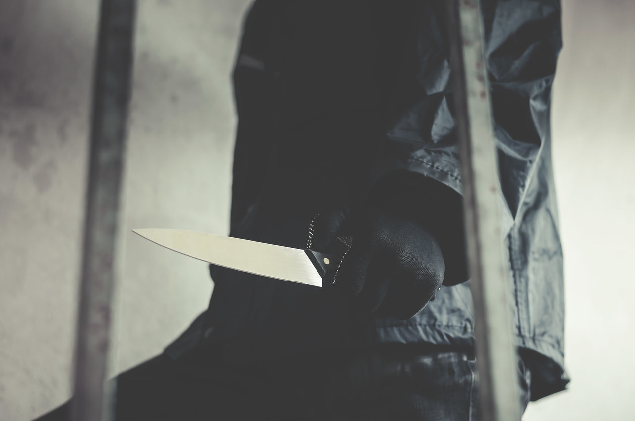 CLOSE-UP OF PERSON HOLDING UMBRELLA STANDING ON A TABLE