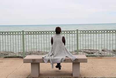 Rear view of woman standing on beach against sky