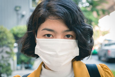 Portrait of beautiful young woman wearing mask standing outdoors