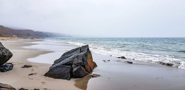 Scenic view of rocks on beach against clear sky