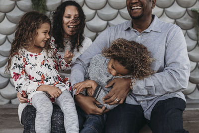 Lifestyle image of happy family tickling each other and laughing while