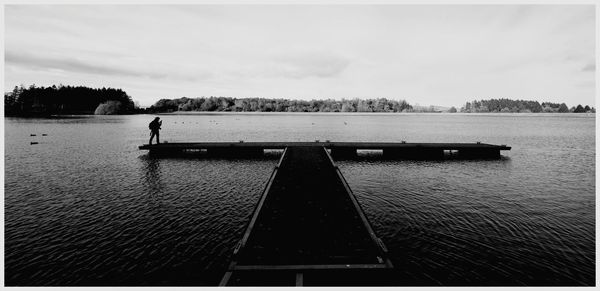 Man standing on pier over lake