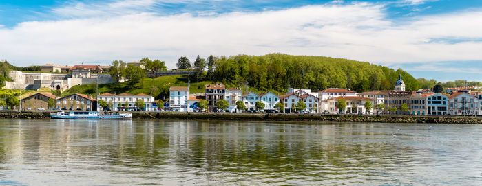 Buildings by river against sky