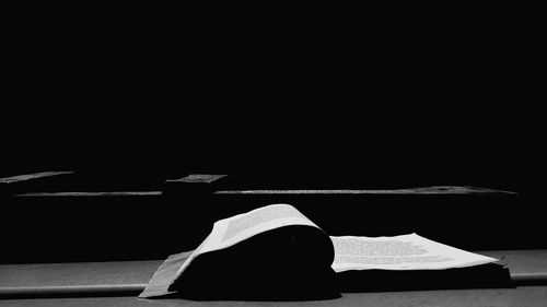 Rear view of senior woman reading book in darkroom