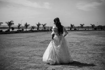 Full length of woman standing on field against sky