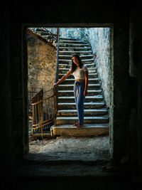 Woman standing on staircase of old building