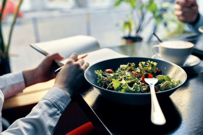 Midsection of chef writing in diary in front of food in plate