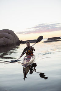 Portrait of confident man kayaking at dusk