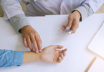 Midsection of doctor examining patient hand in hospital