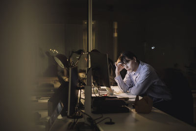 Tired young businesswoman working at desk in office