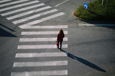 High angle view of woman walking on zebra crossing at street